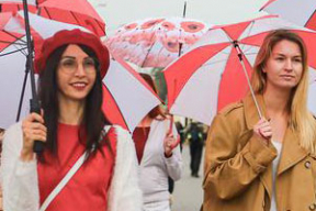 Красавицы с бело-красно-белыми зонтиками гуляют по Минску